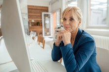 Mature Businesswoman In Front Of Desktop PC At Office Desk