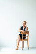 © Westend61 - Businesswoman sitting on chair in front of white wall