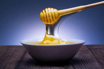 Wall Mural - honey drips from the spoon into a white bowl with