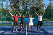 © Westend61 - Happy men and women with arms raised standing at sports court