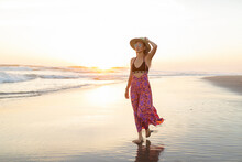 Young Woman With Hat Walking On Shore At Beach