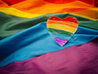 A rainbow heart shape symbol made from paper over the rainbow flag or LGBT flag