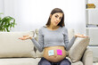 © Andrii - Photo of positive pregnant woman with pink and blue papers on the stomach which mean gender of her future baby.