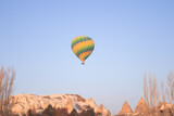 Fototapeta  - A bright green hot air balloon flying over the mountains landscape