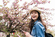 © PR Image Factory - portrait of pretty asian girl wearing hat smiling at camera against blurred background of pink cherry blossom trees at springtime in mint museum in Osaka, japan
