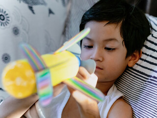 Candid shot of 6 years old Asian little boy with recycle bottle plane.