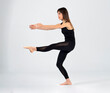 © pedro - Young sporty yogi woman practicing yoga, doing Wild Thing, pose, working out, wearing sportswear, black pants and top, indoor full length, white yoga studio