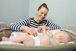 © Elroi - mother puts  diaper to a baby lying in a crib