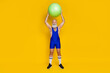 Full length photo of joyful strong masculine trainer raise ball intense cardio regime spend time gym isolated on yellow color background
