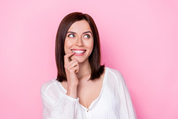 Poster - Photo portrait of adorable young girl look tricky empty space bite nail dressed stylish white garment isolated on pink color background