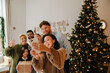 © Drobot Dean - Cheerful family taking selfie while standing together near Christmas tree