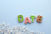 Overhead View Of Letter Cookies Spelling DATE On Blue Background With Snowflakes