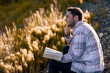 © Designpics - A young man reads from his Bible as he sits in the countryside; Alberta, Canada