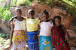 Outdoor shot of four young pretty African sisters posing with arms around shoulders looking at the camera with proud and serious expressions on their faces.