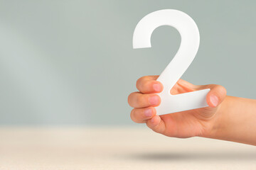 Fototapete - Number two in hand. Hand holding white number 2 on blurred background with copy space. Concept with number two. 2 percent, birthday 2 years old, couple, two, double
