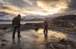 © Designpics - View taken from behind of two kids playing in the icy pools with another hiking on the outpost above, at Beluga Point in Turnagain Arm of Cook Inlet at sunset;  Alaska, United States of America