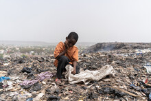 Miserable Hungry African Slum Child Looking For Edible And Recyclable Items In A Huge Urban Garbage Dump