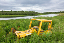 Rusted Vintage Yellow Catapiller Tractor Overgrown With Foliage, Kuskokwim River; Kalskag, Southwestern Alaska, Alaska, United States Of America