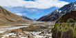 © Designpics - Icy valley with mantra painted on rock and snow capped mountains behind in the foothills of the Himalayas in the Ladakh Region; Jammu and Kashmir, India