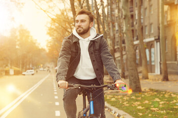 Wall Mural - Happy handsome man riding bicycle in city on sunny day