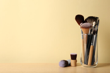 Wall Mural - Set of professional makeup brushes on wooden table against beige background, space for text