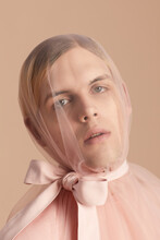 Close-up Portrait Of Young Man In Transparent Tulle With Pale Pink Bow Looking At Camera