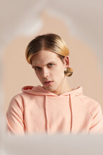 Portrait Of Lad Wearing Pastel Peach Hoodie And One Golden Earring Looking At Camera