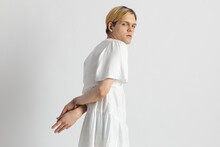 Horizontal Shot Of Male Model Wearing White Dress Keeping Hands Behind His Back And Looking At Camera