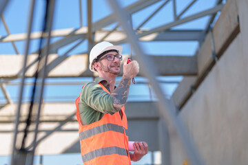 Wall Mural - Two professionals inspect construction site of commercial building, industrial building, real estate project  civil engineer, investor using laplet in background crane, skyscraper, concrete formwork