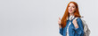 Waist-up portrait joyful cute redhead girl inviting freshmen apply univeristy, got scholarship, smiling showing thumbs-up in approval, recommendation, holding backpack and headphones