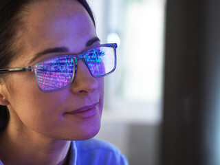 female expert in glasses looking at screen with financial data