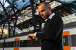© ADDICTIVE STOCK - Black businessman checking time on wristwatch while standing on railway platform