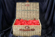 An isolated wicker hamper full of red rose petals