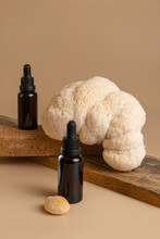 Two Bottles Of Dark Amber Glass With Essential Oil With Beautiful Lion Mane Mushroom On Beige Background