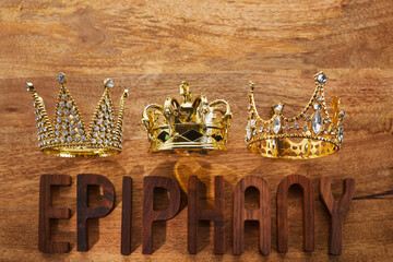 Poster - Happy Epiphany day. Three gold crowns on wooden background, symbol of Tres Reyes Magos, Three Wise Men. 