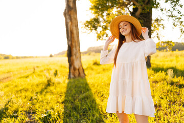 Wall Mural - portrait of dreamy smiling young woman in straw hat and white dress standing posing with closed eyes