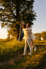 Wall Mural - vertical shot of loving young couple hugging kissing with closed eyes on green meadow in summer even