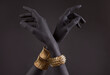 Black woman's hand with gold jewelry. Oriental Bracelets on a black painted hand. Gold Jewelry and luxury accessories on black background closeup