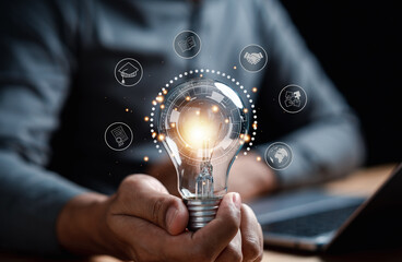 Fototapete - Man hand holding lightbulb with learning educate and graduation concept. study knowledge to creative thinking idea and problem solving solution, E-learning online education course degree certificate