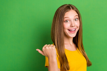 Wall Mural - Profile photo of cheerful funky girl toothy smile indicate thumb finger empty space isolated on green color background