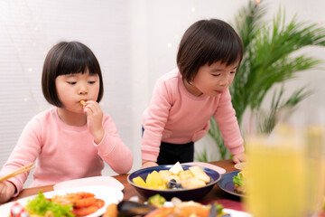 Canvas Print - テーブルに並べられたクリスマスの料理を食べる子供