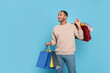 © New Africa - Happy African American man with shopping bags on light blue background