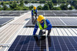 © Tongpool - Engineer on rooftop kneeling next to solar panels photo voltaic with tool in hand for installation
