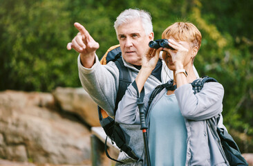 Wall Mural - Elderly, couple hiking and fitness, adventure outdoor with hike together, active lifestyle with freedom and travel. Nature, trekking and senior man pointing and woman with binocular for bird watching