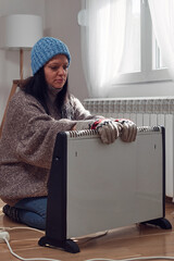 Wall Mural - Woman in jacket, sweater and hand gloves indoors on a chilly winter day, energy and gas crisis, cold room, heating problems.