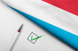 pencil, flag of Luxembourg and check mark on paper sheet
