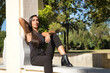 © Manuel - Young woman, brunette, slender and dressed in black, sitting on a bench with a lost look, thoughtful and serious, receiving the rays of the sun. Concept beauty, fashion, thinking, seriousness.