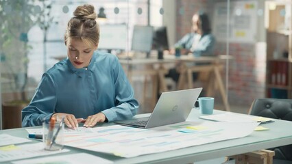 Poster - Portrait of White Creative Young Woman Working on a Laptop Computer in Bright Office. Female Team Lead Smiling While Checking her Team Performance Data. Colleague Working in Background. Arc Shot