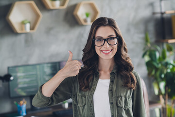 Photo of smiling cheerful lady engineer wear spectacles showing thumb up indoors workplace workshop