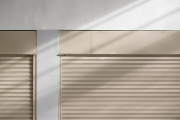 Wall Mural - Light and shadow on part of 2 beige steel roller shutter doors of warehouse, front view with copy space